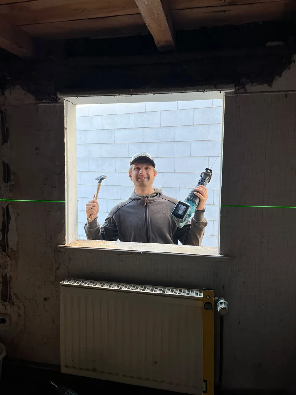 Maik Sykow mit Hammer und Säbelsäge an einer Fensteröffnung